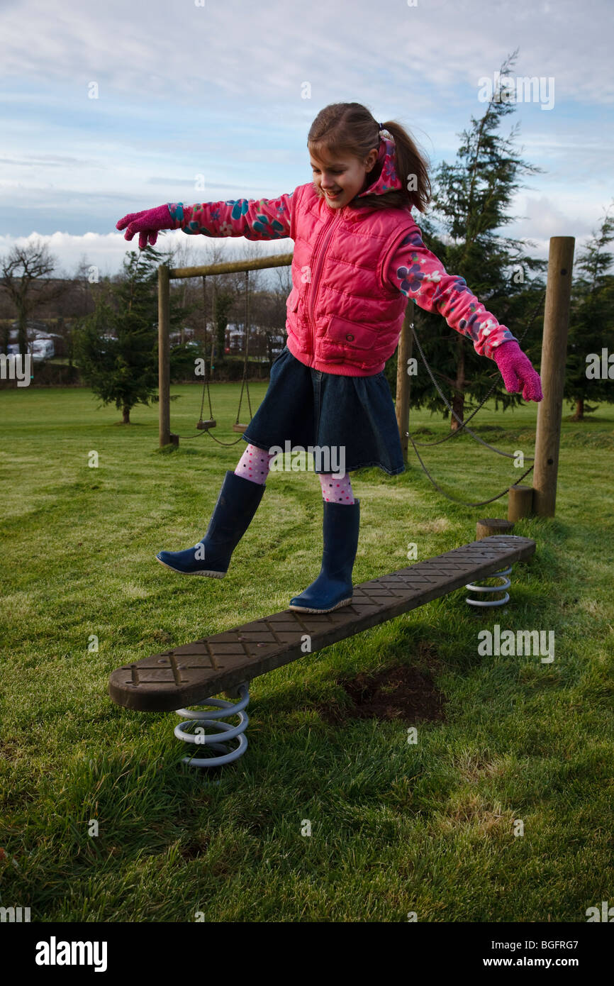 Girl balancing on wooden obstacle course. Stock Photo