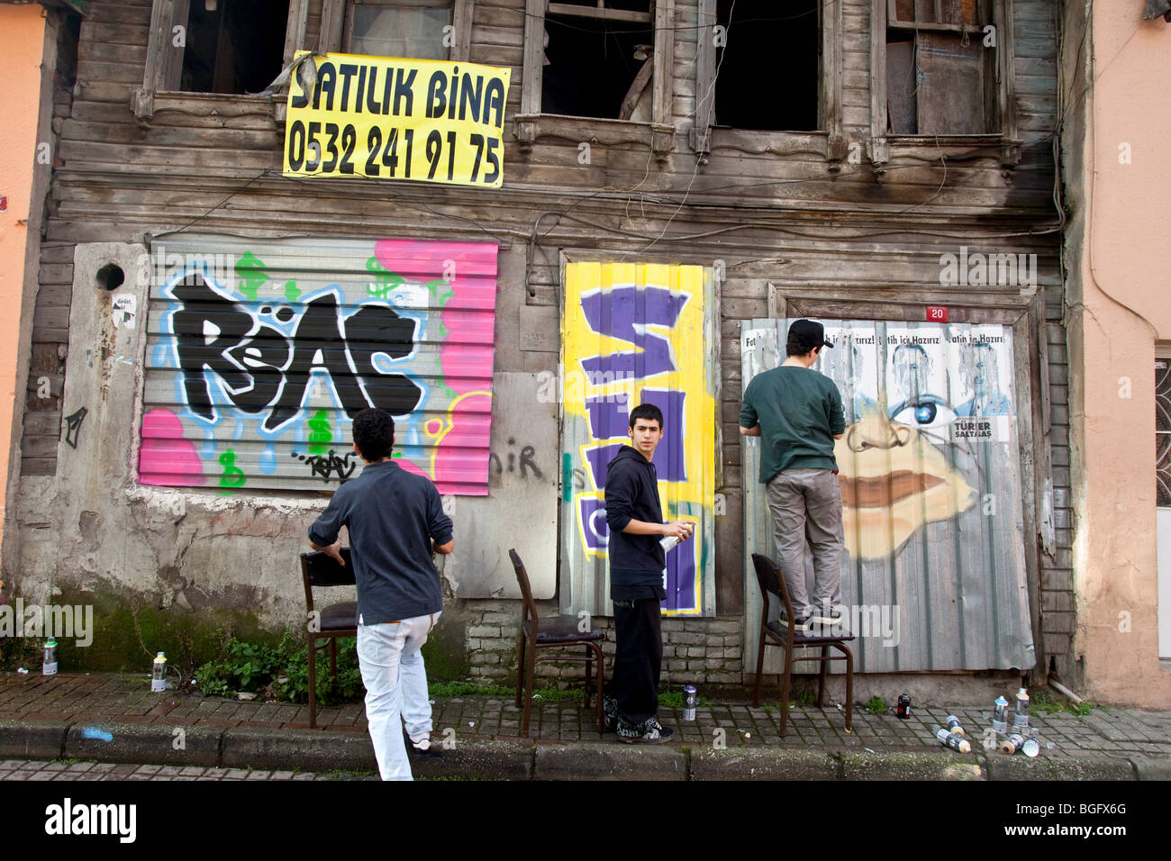 Turkish youth painting graffiti on an old wooden Ottoman house, Istanbul Turkey Stock Photo