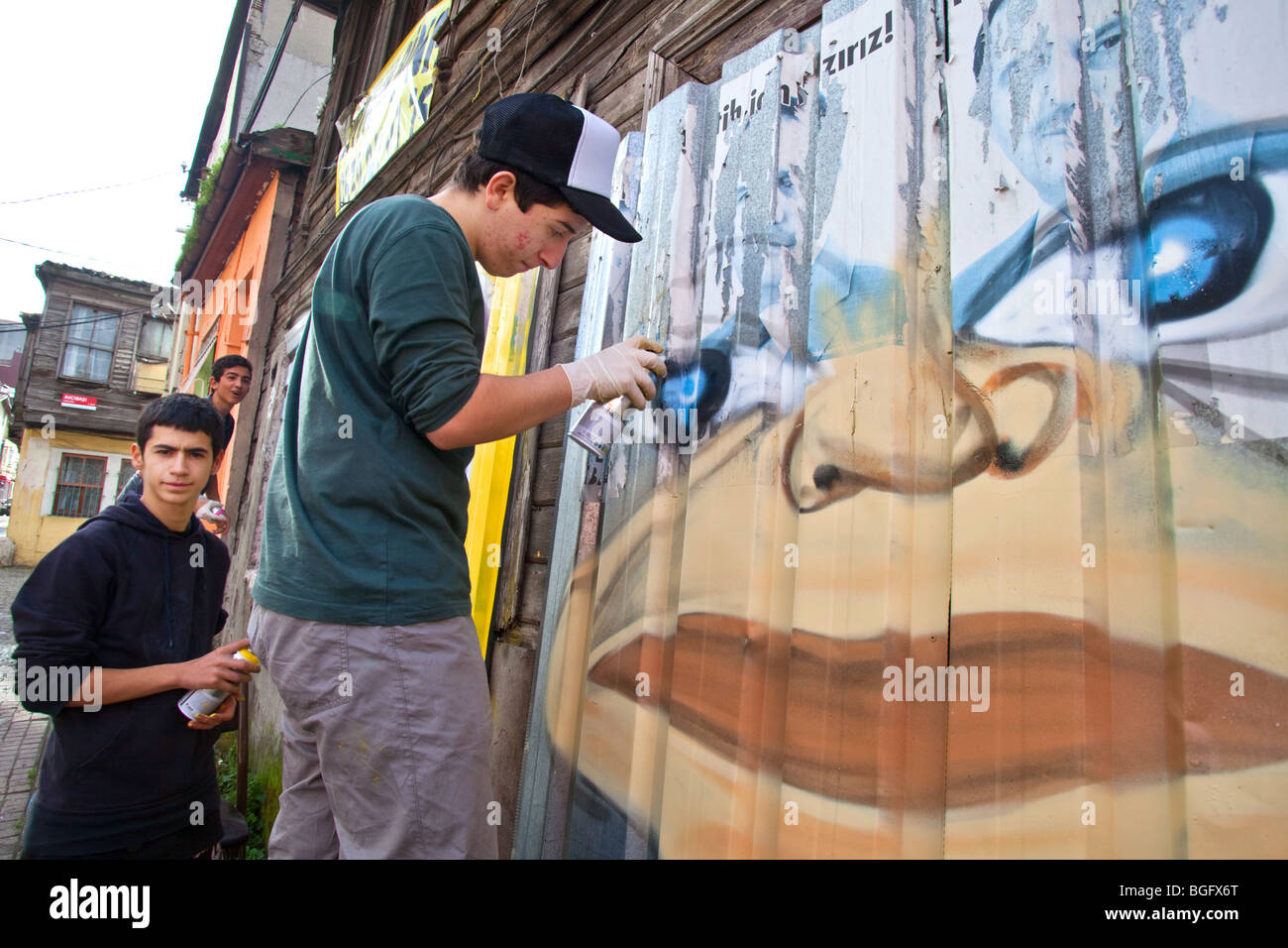 Turkish youth painting graffiti on an old wooden Ottoman house, Istanbul Turkey Stock Photo