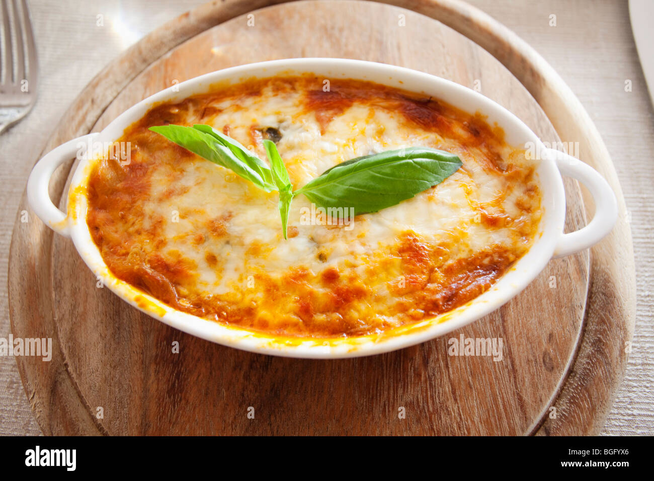 Baked lasagna with a golden cheese crust garnished with a fresh basil ...