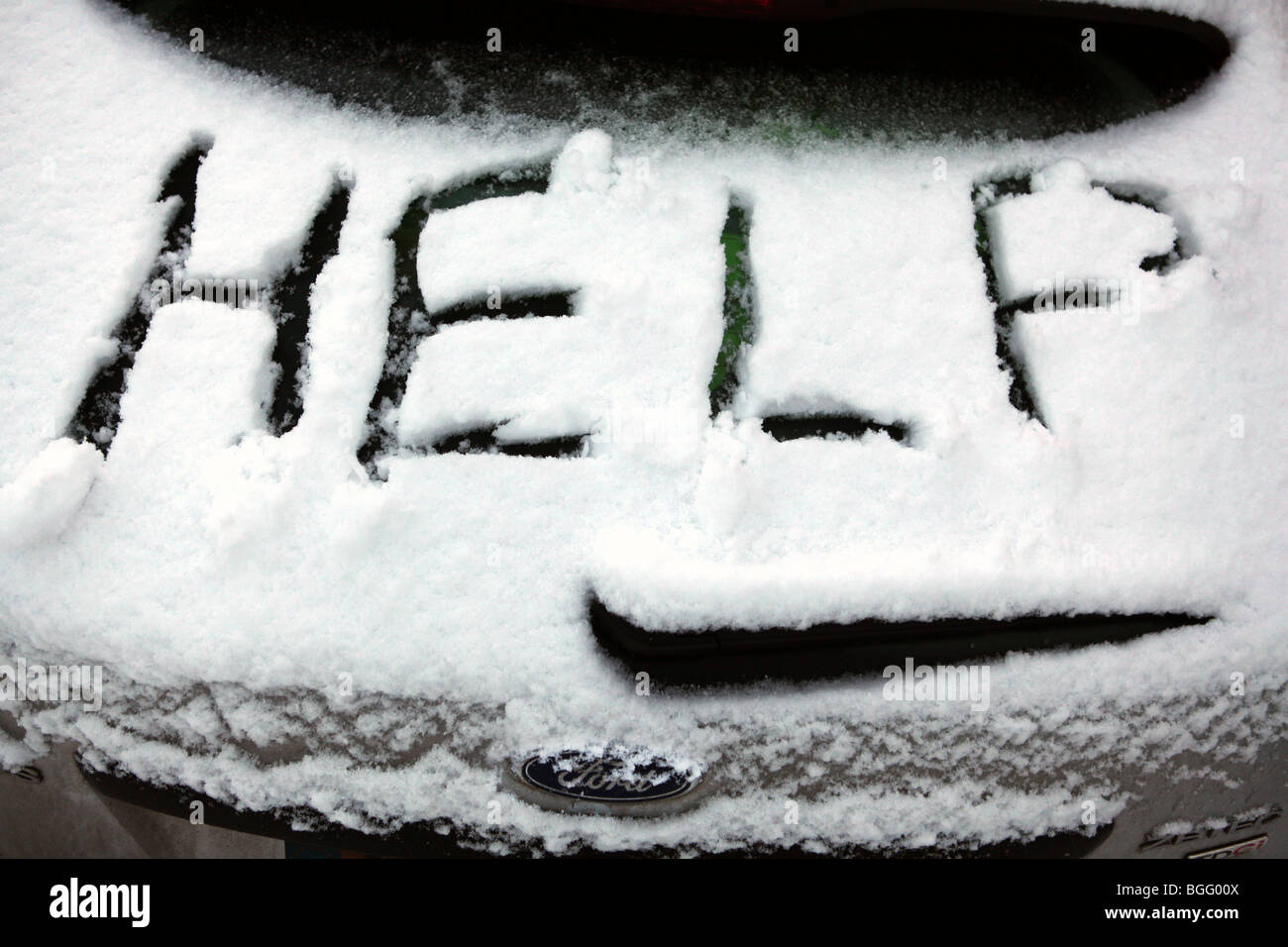 A car stranded in severe Winter weather conditions with the word help written on the snow during the Big Freeze of 2010 Stock Photo