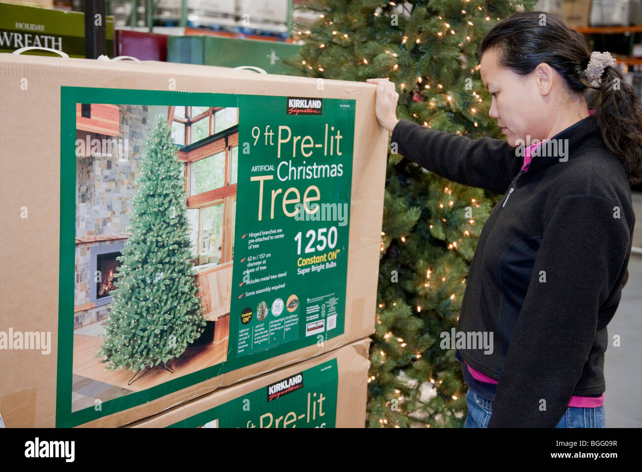 Mid adult woman shopping for an artificial Christmas tree with lights. California, USA Stock Photo