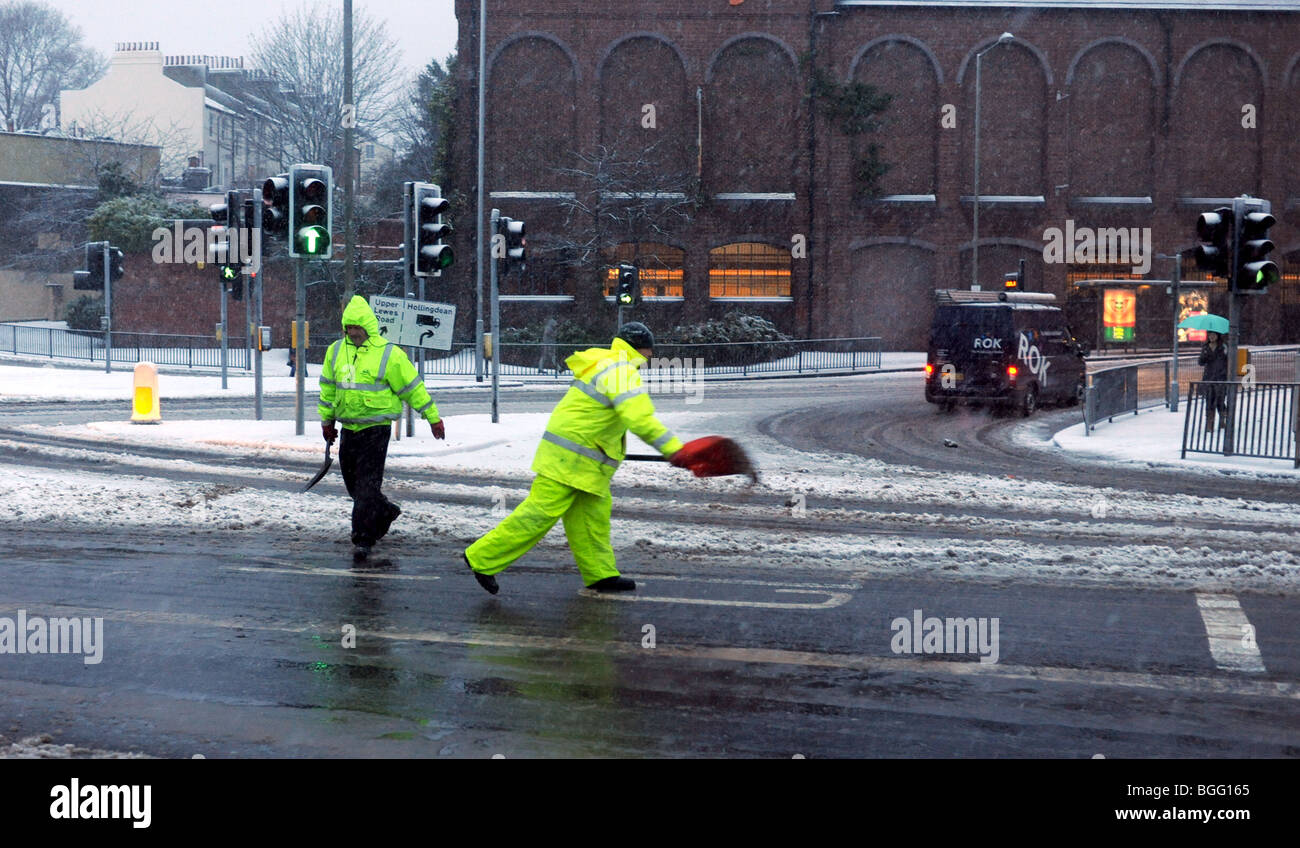 Council workers spreading grit and salt by hand on roads during snow