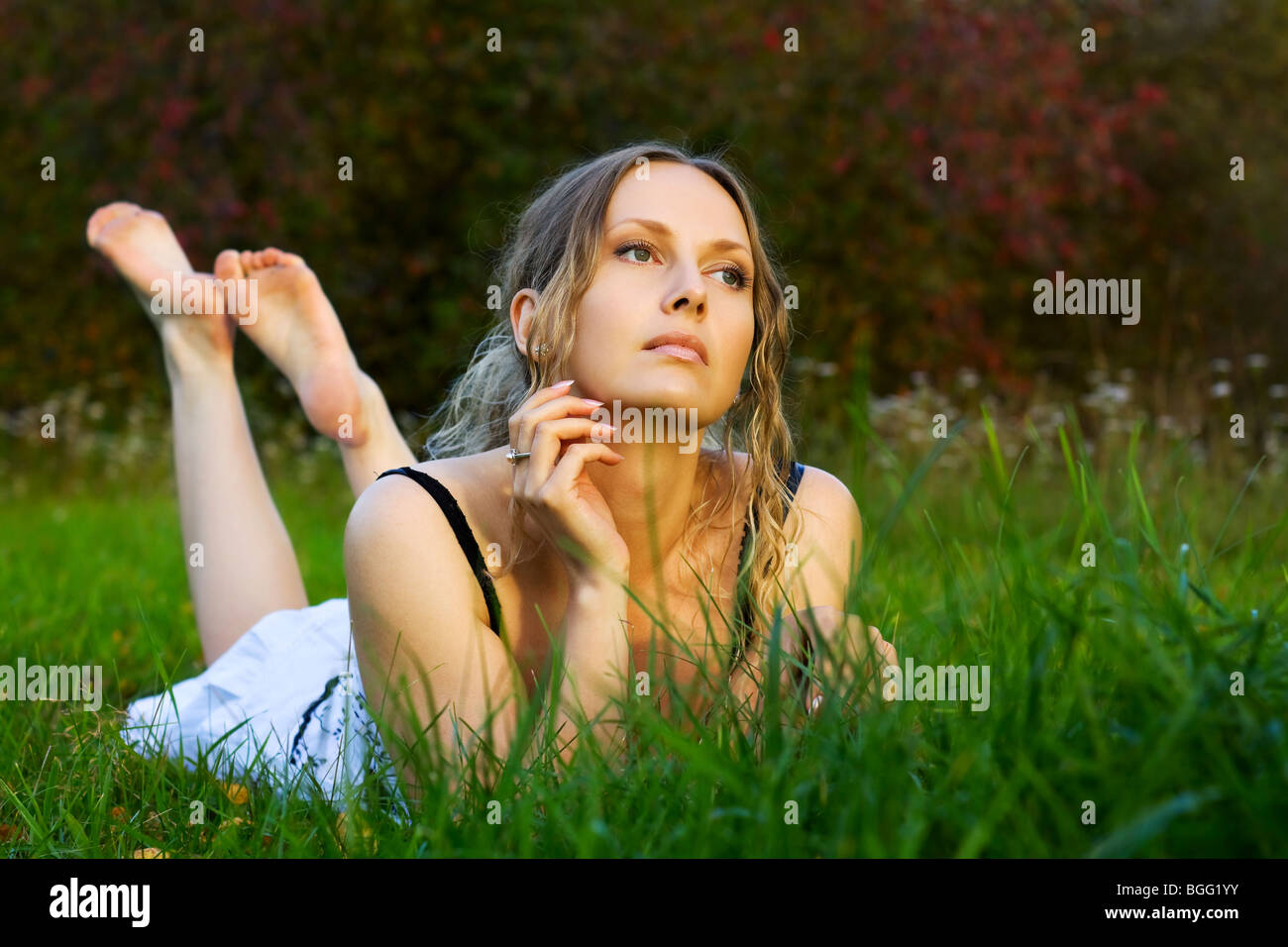 Beautiful young woman lying on the green grass Stock Photo - Alamy