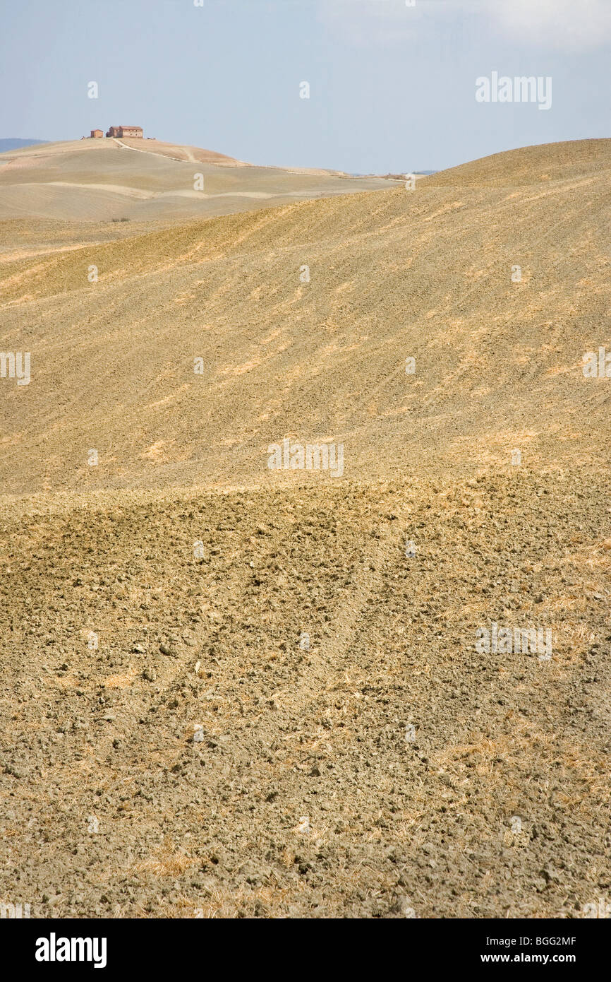 Barren minimalist landscape of The Crete area near Sienna in Southern Tuscany Italy with open ploughed fields and hilltop farm Stock Photo