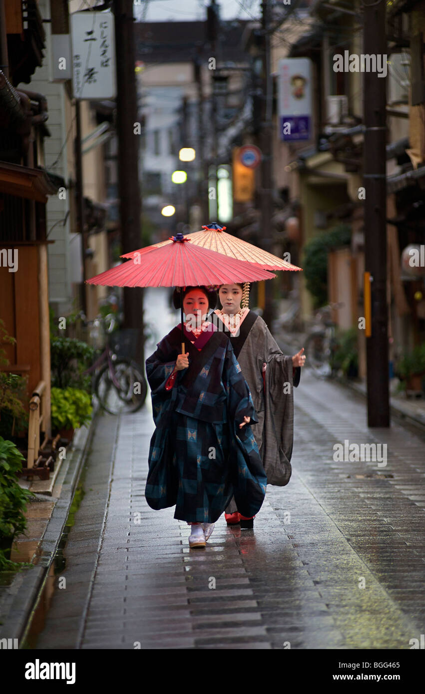 Japanese Maiko heading out to an early evening appointment in the rain with traditional umbrella, Kyoto, Japan Stock Photo
