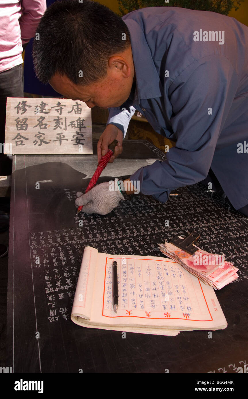 Man engraving the names of contributors of the Zhiyuan temple on a stone tablet. Jiuhua Shan. Anhui province, China Stock Photo