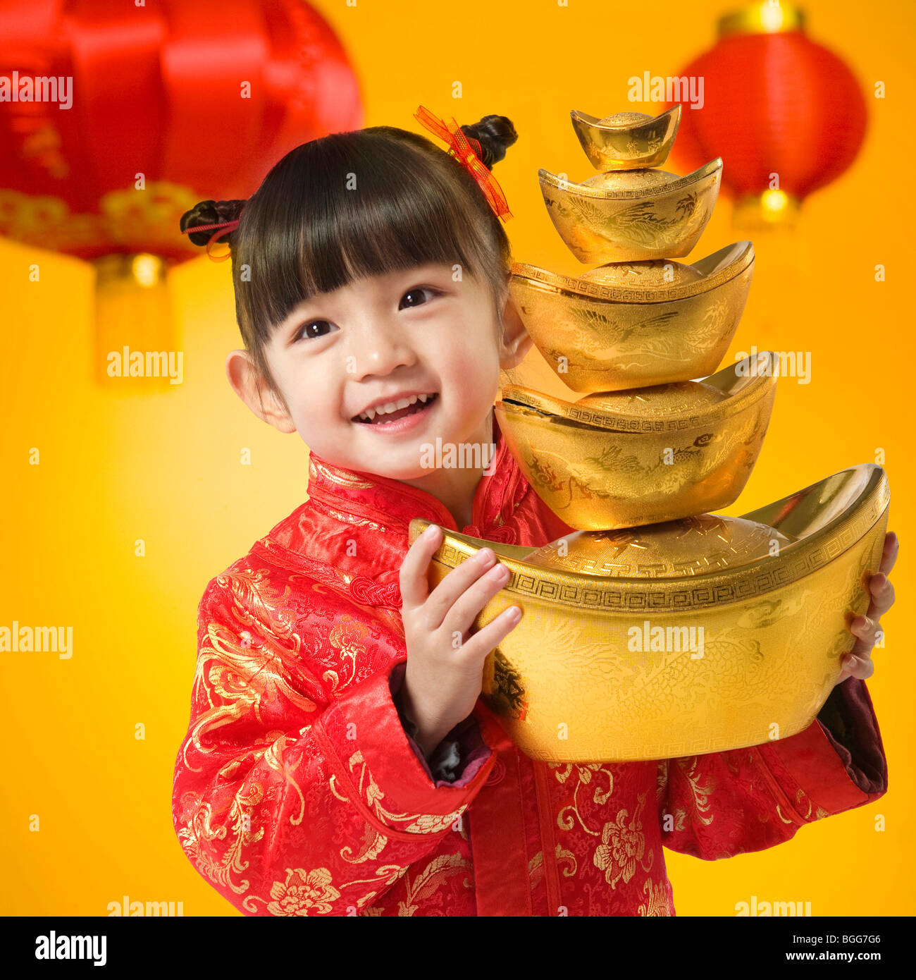 Girl in Chinese traditional clothes holding gold ingot Stock Photo