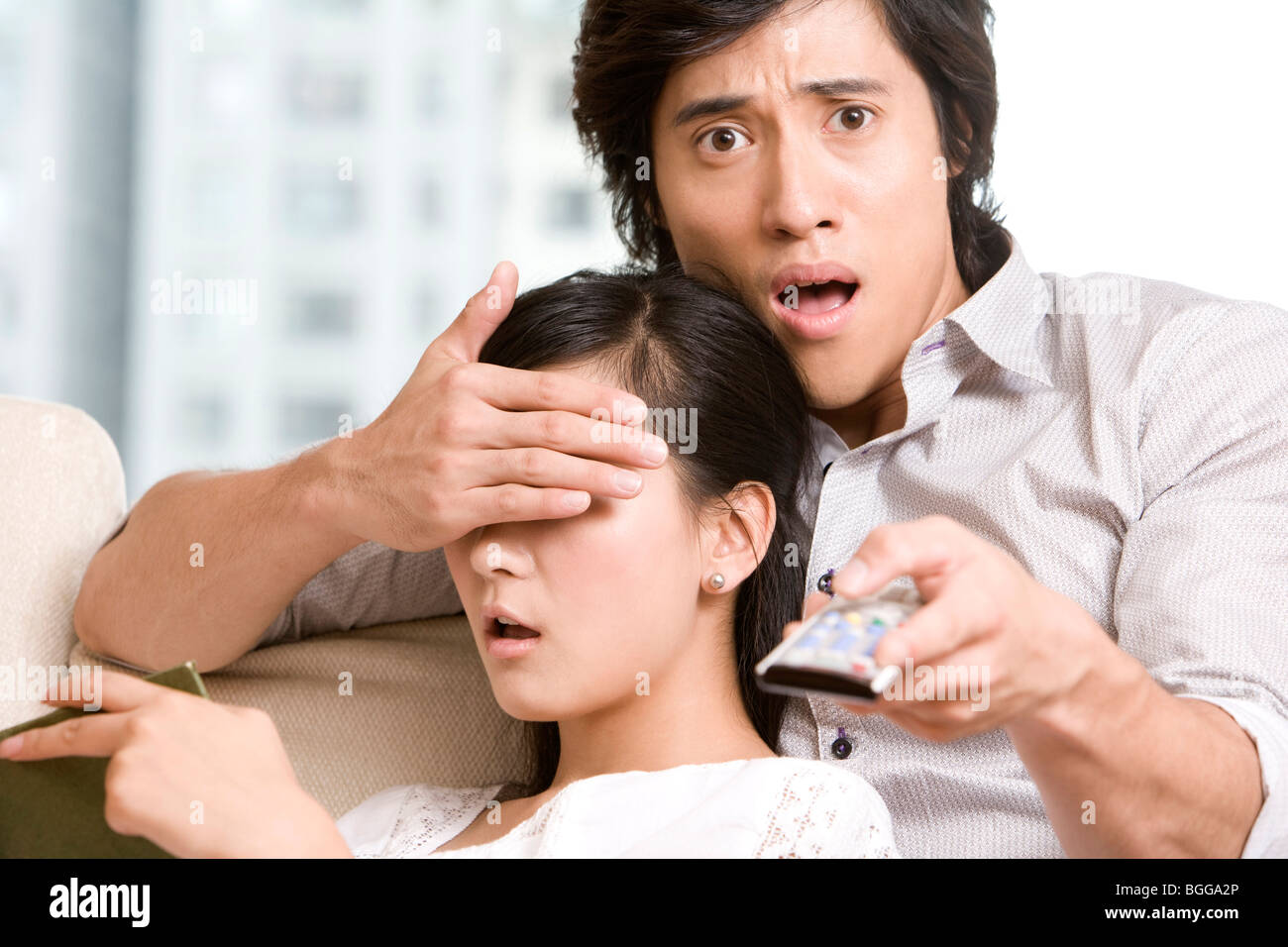 Asian couple cuddling on a sofa Stock Photo Alamy