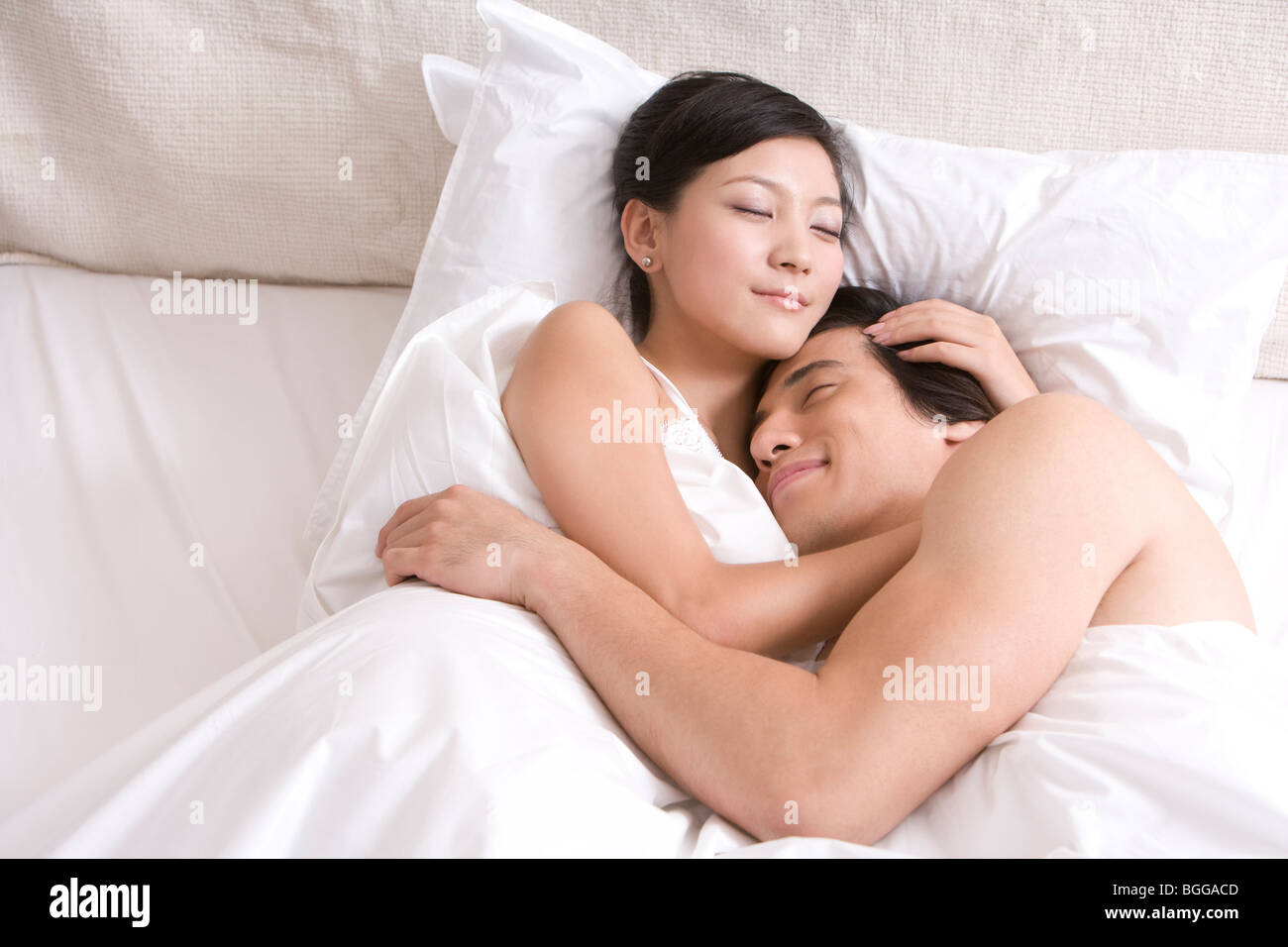 asian-couple-cuddling-on-bed-BGGACD.jpg