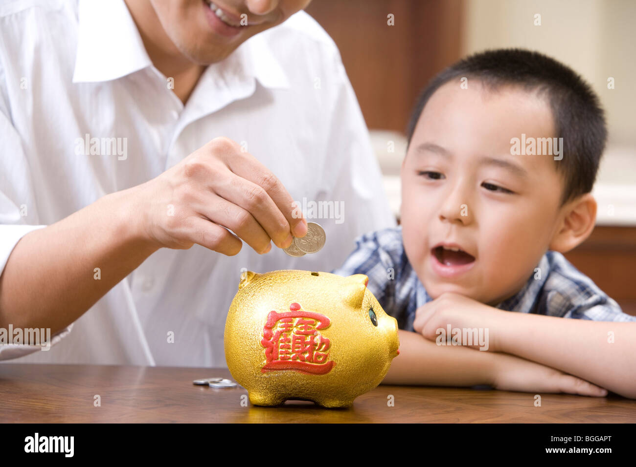 Father and son saving coins into a piggy bank Stock Photo - Alamy