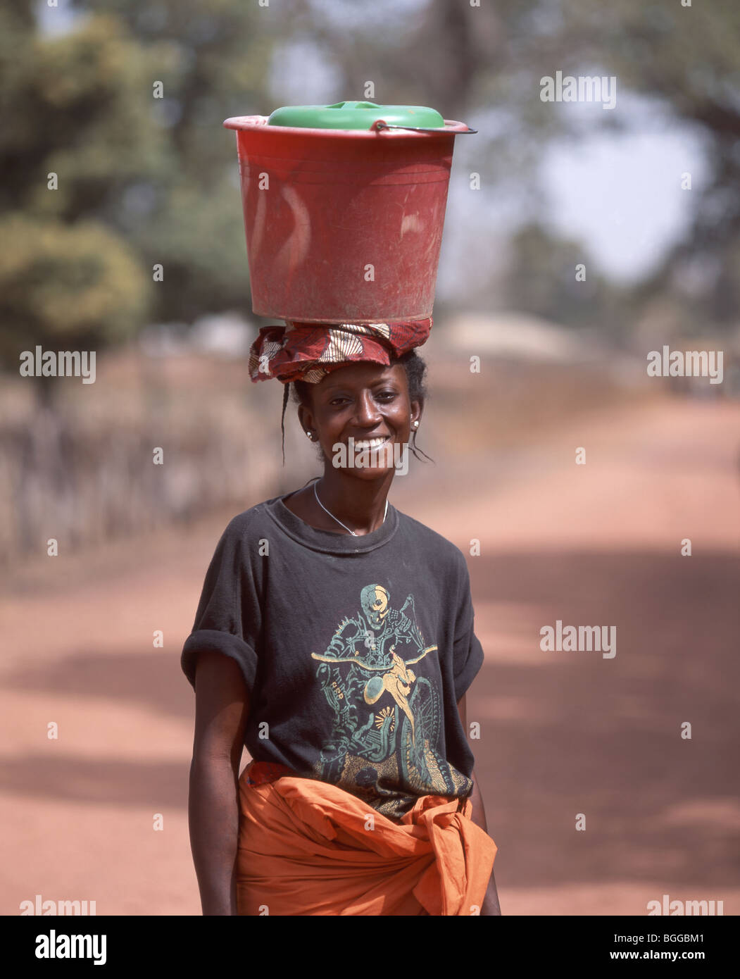 Local village woman carrying bucket on head, Juffure, North Bank Division, Gambia Stock Photo