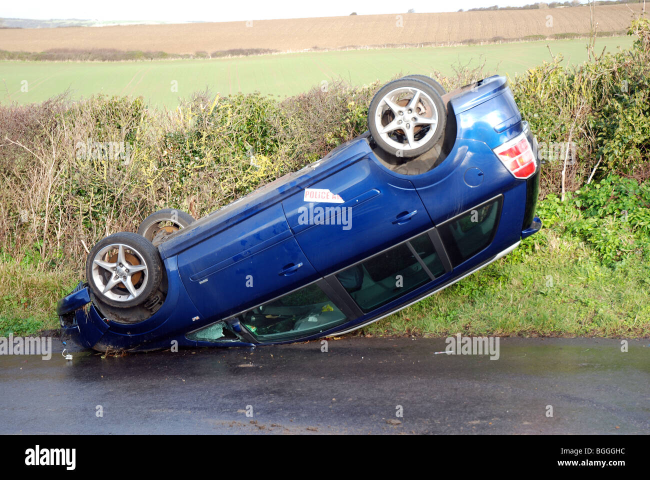 An upturned car in a country lane Stock Photo