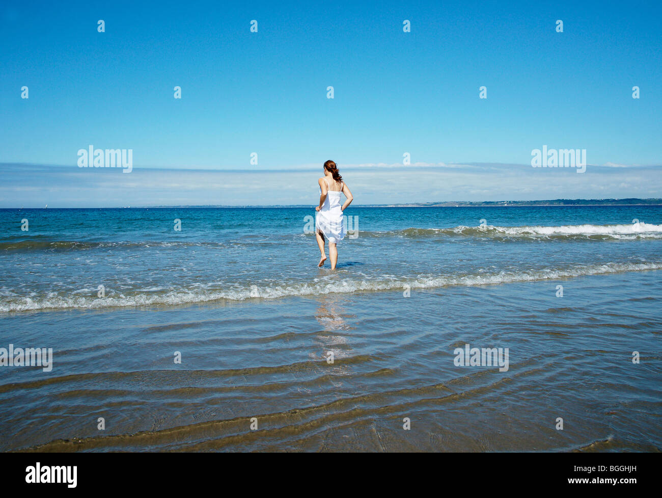Woman entering the water, rear view Stock Photo