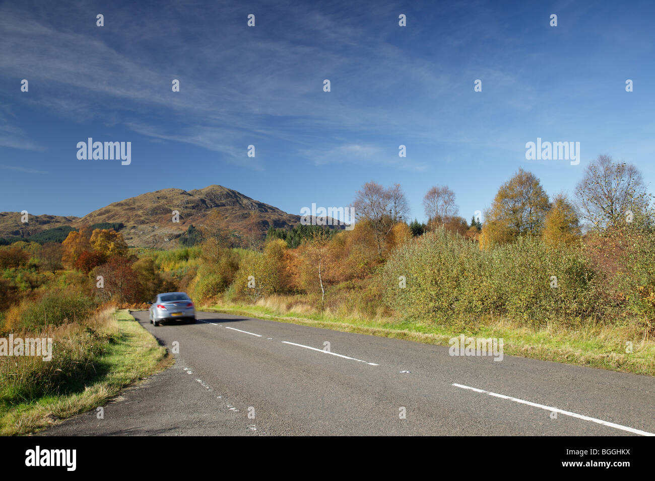 Ben Venue in Autumn, mountain in the Loch Lomond & Trossachs National Park, and a motion blurred car on the A821 Dukes Pass road trip, Scotland, UK Stock Photo