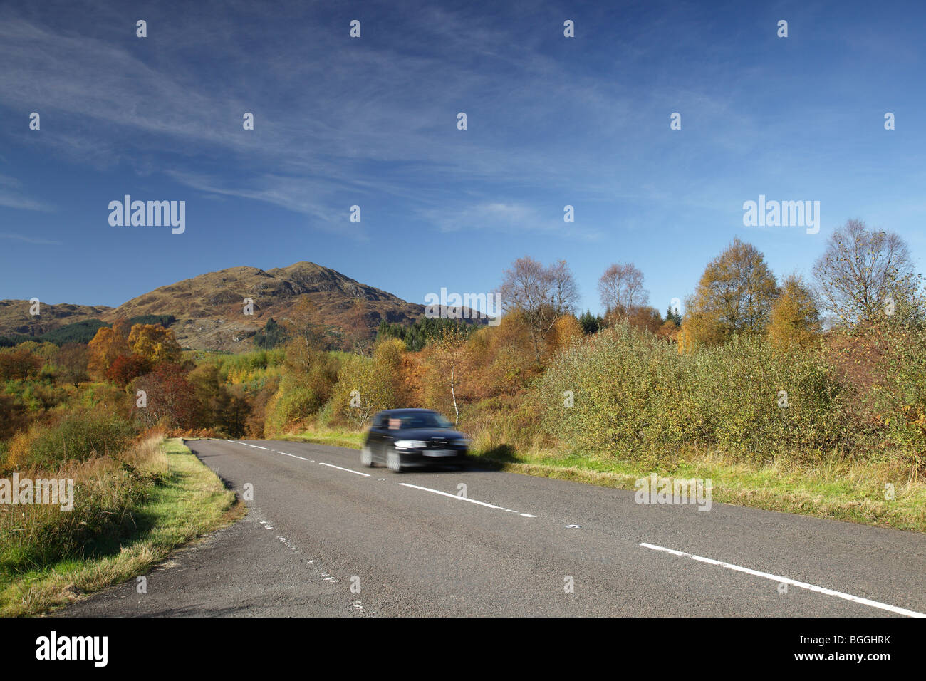 Ben Venue in Autumn, mountain in the Loch Lomond & Trossachs National Park, and a motion blurred car on the A821 Dukes Pass road trip, Scotland, UK Stock Photo