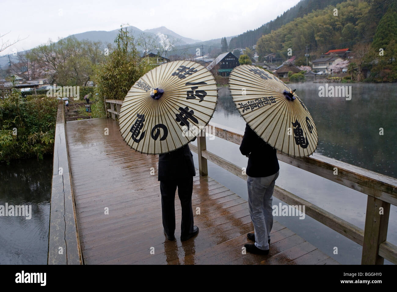 two people with umbrellas standing on a bridge, Yufuin, Japan, rear view Stock Photo