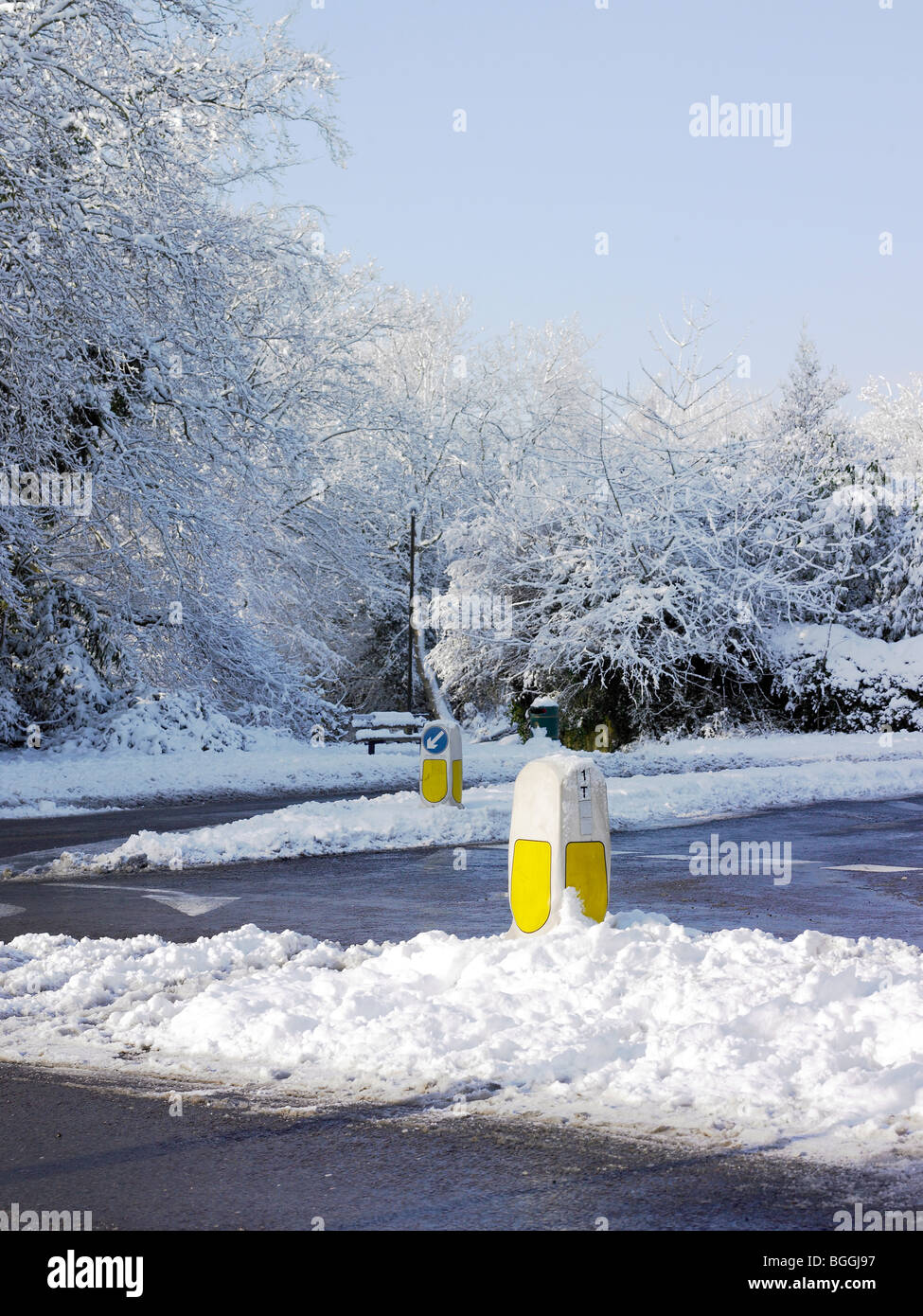 Two keep left bollards in the snow, with a cleared / slushy roads Stock Photo