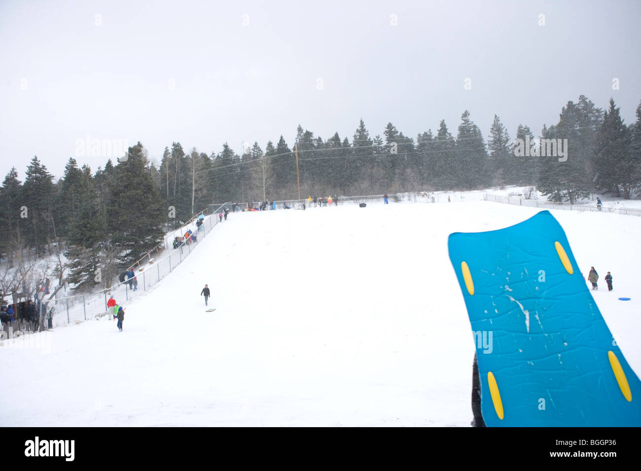 a man holds a sled after sledding down a hill, Capulin snow play 