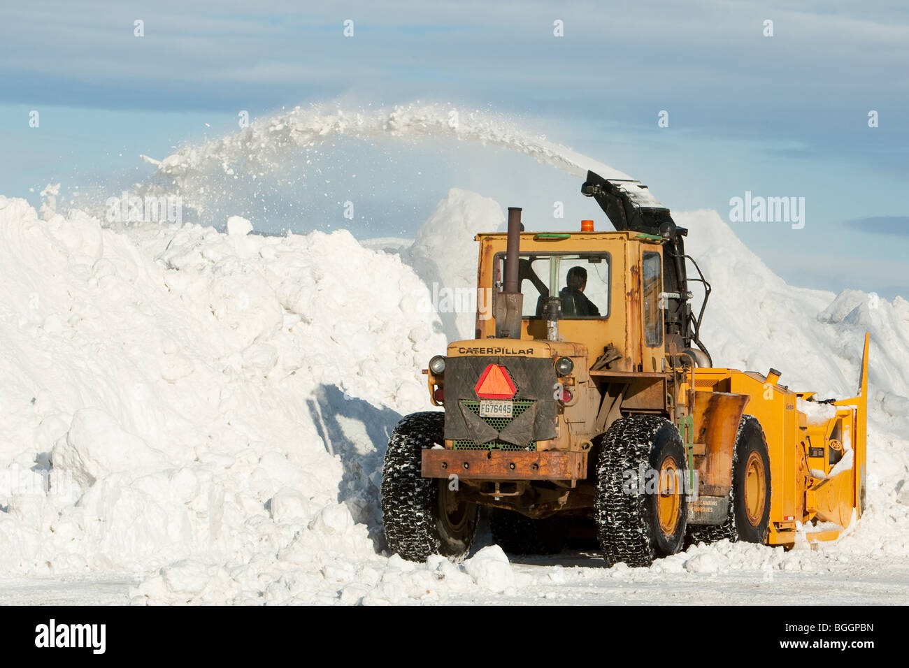 A Caterpillar snowblower blows snow from a parking lot Stock Photo