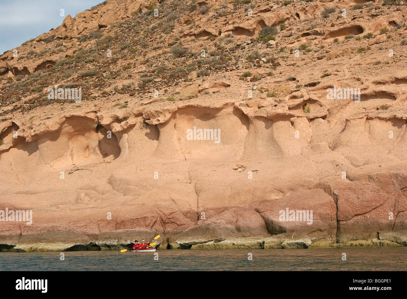 Kayaking in the Sea of Cortez alongside weathered basalt cliff. Baja