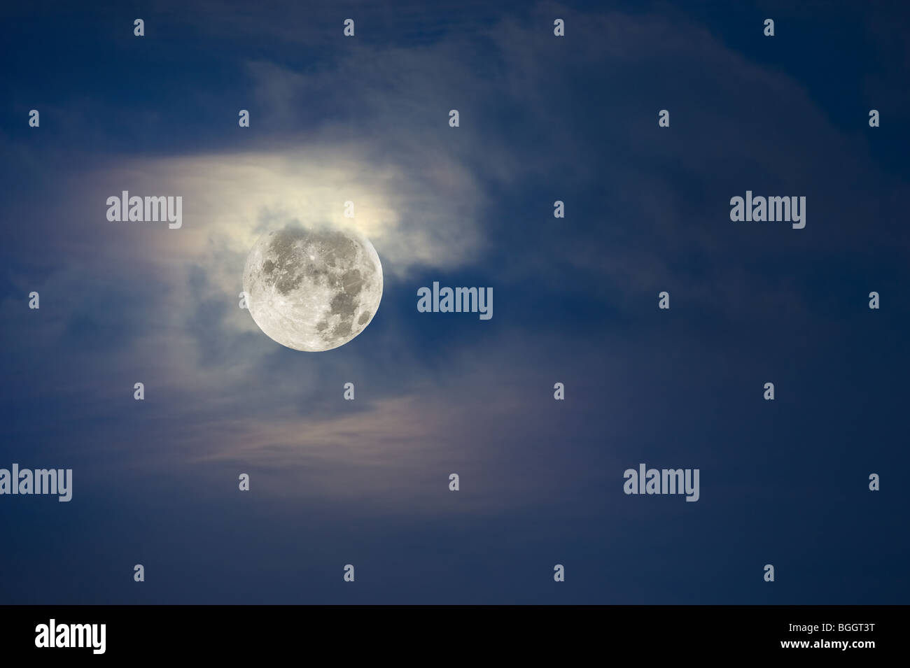 A brightly lit full moon lights up the cloudy, hazy sky. Stock Photo