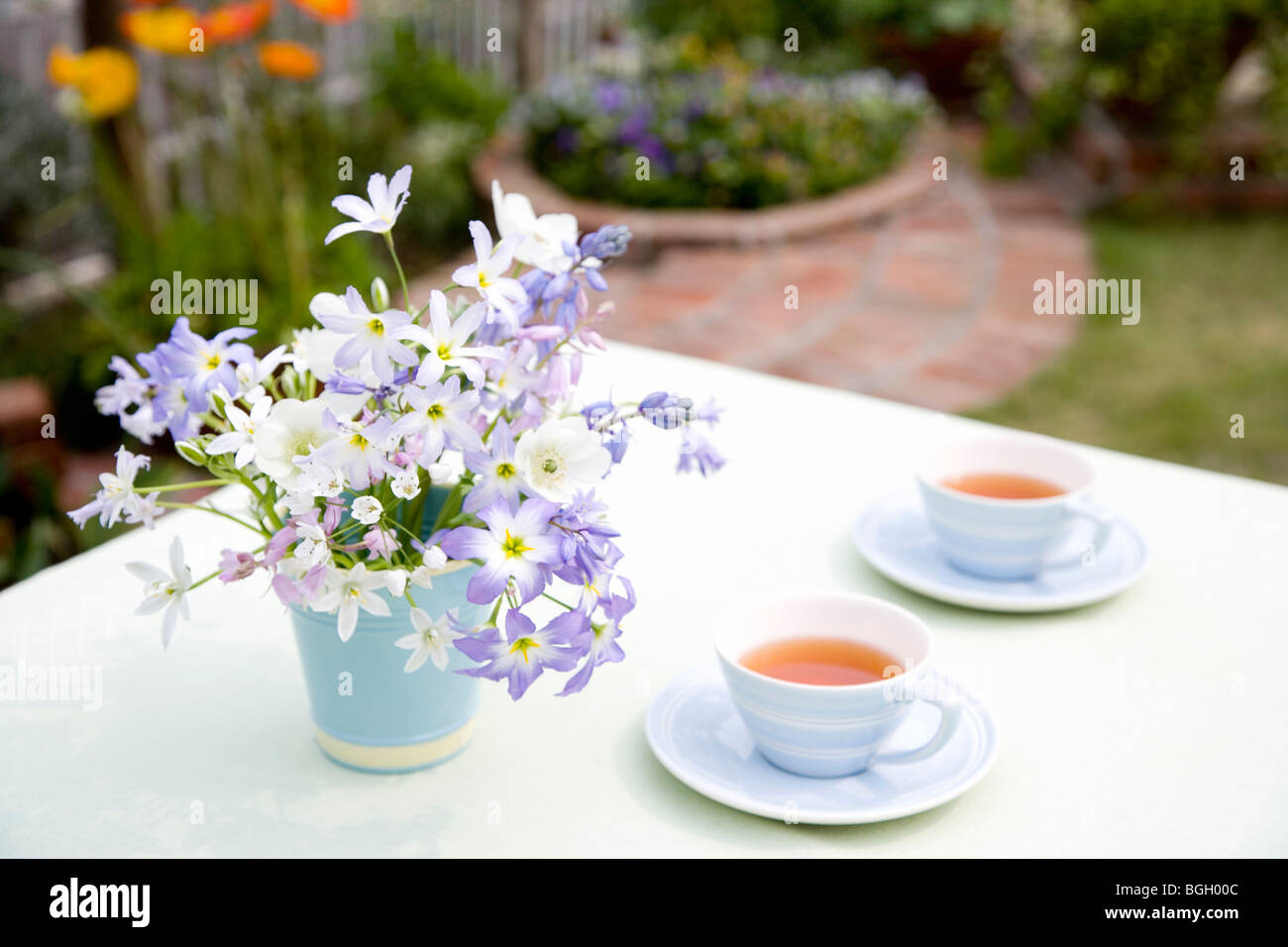 Cups of tea and bunch of flowers on an outdoor table Stock Photo