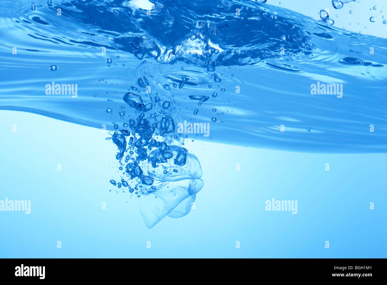 Ice cubes dropped in water close up blue background Stock Photo - Alamy