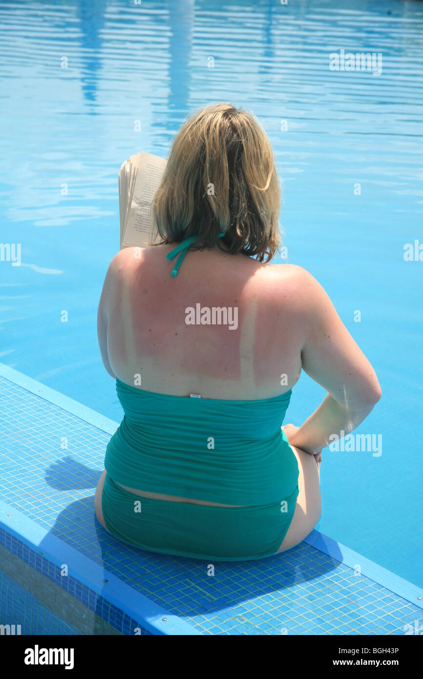 Woman in swimsuit reading book by swimming pool Stock Photo - Alamy