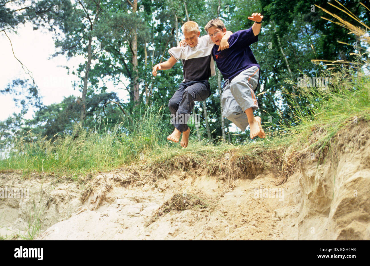 two young boys jumping off a sand dune together Stock Photo Alamy