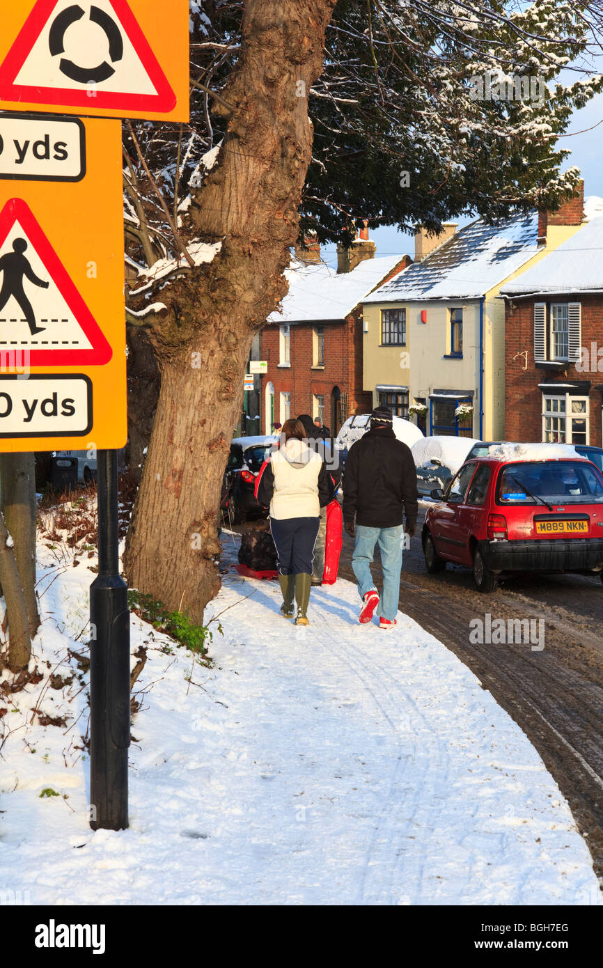 Snowcovered Village of Herne, Kent, UK, with people walking in the snow and cars passing Stock Photo