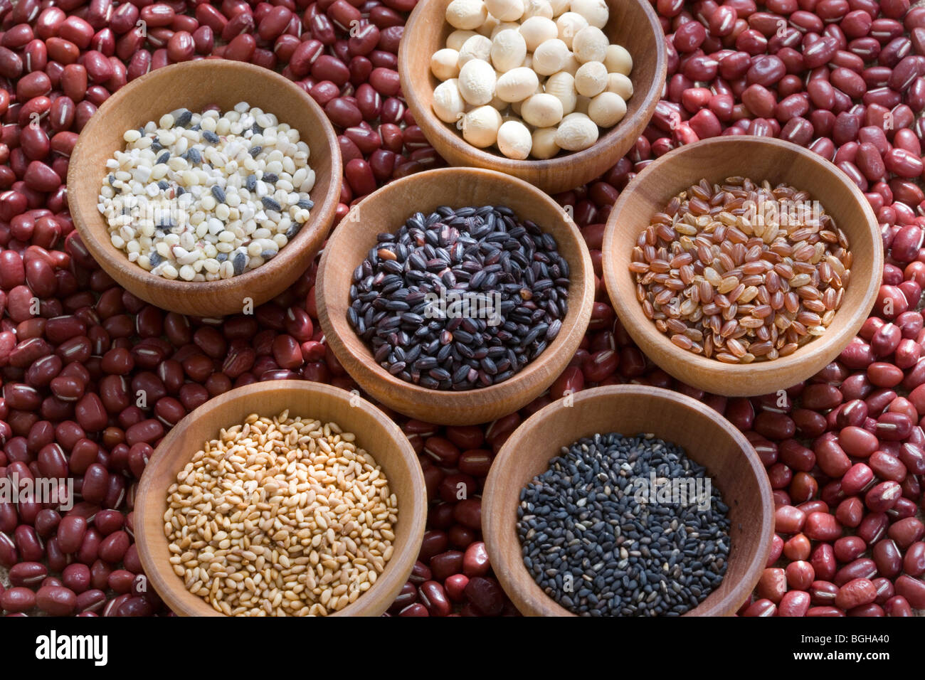 Wooden bowls of different grains rice and beans on top of adzuki beans Stock Photo