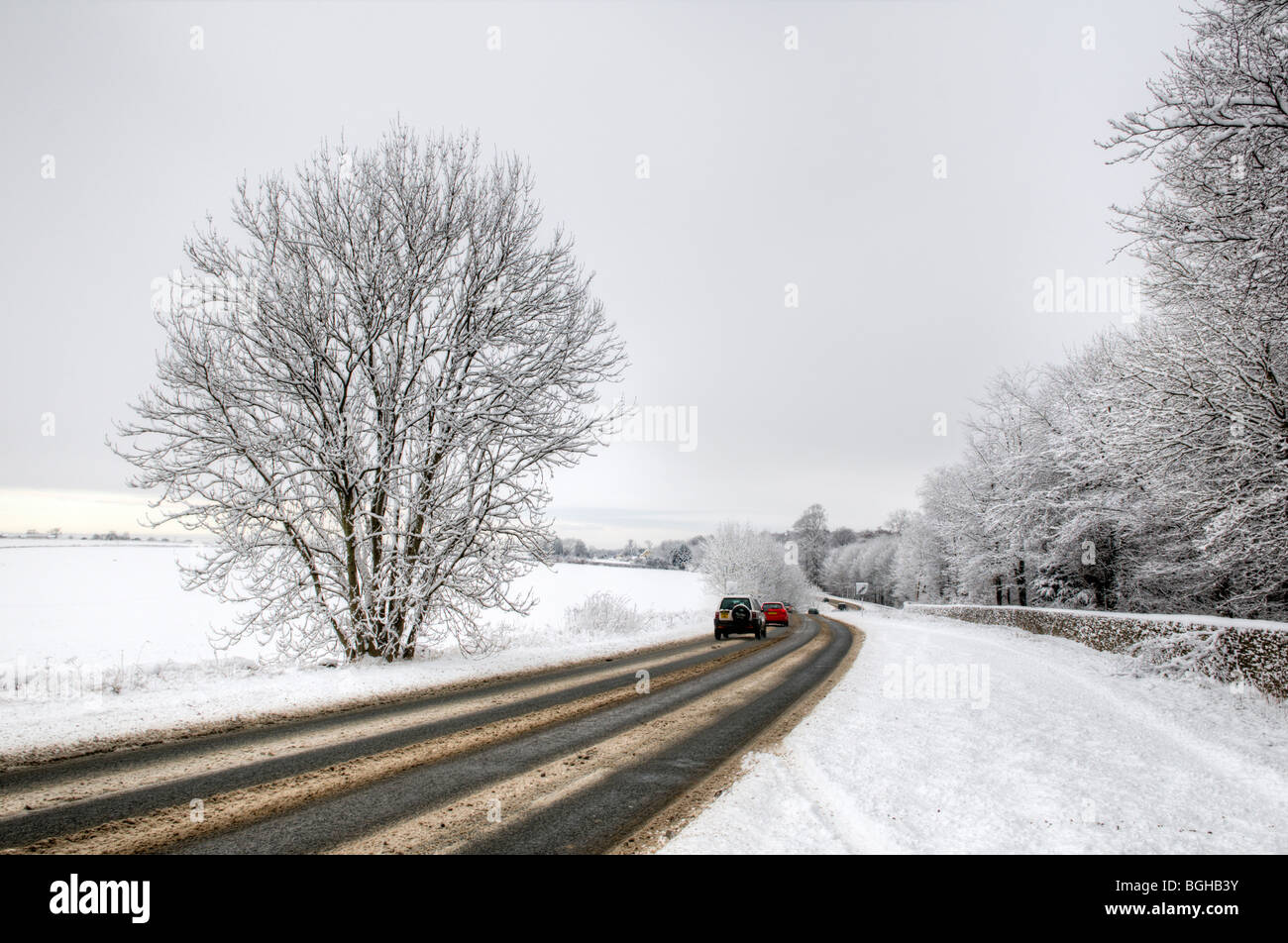 Snowy road scene along the A433 in the Cotswold district with road traffic, taken just after the A46 junction Stock Photo