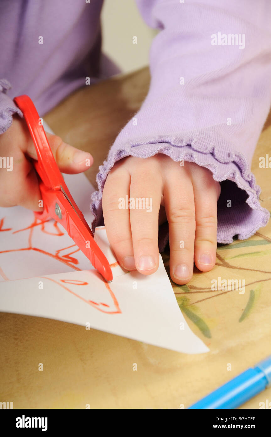 2 year old blonde girl cutting paper with blue children's scissors Stock  Photo - Alamy