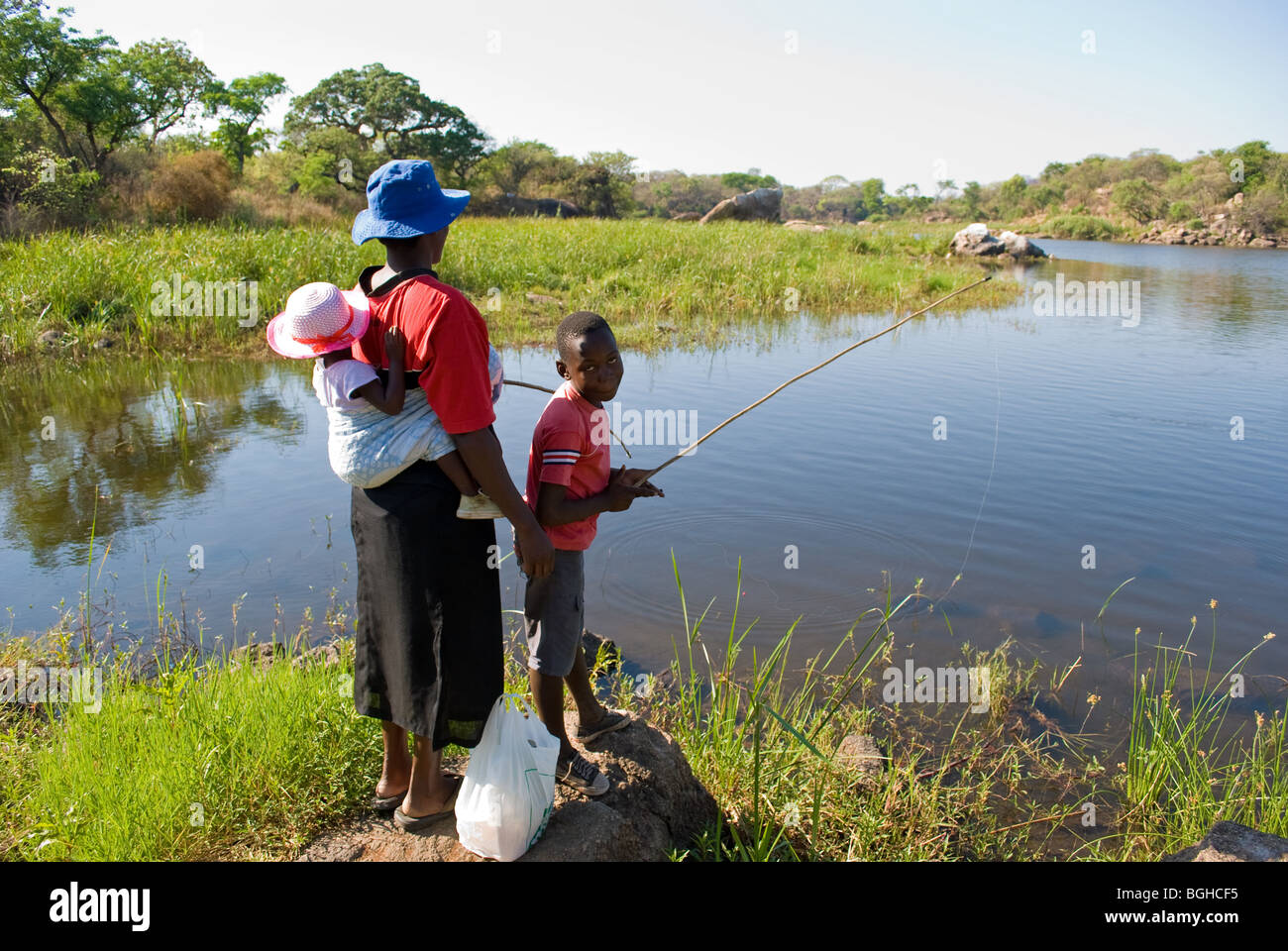A mother and her son fish for food at Hillside Dams in Bulawayo, Zimbabwe. Stock Photo