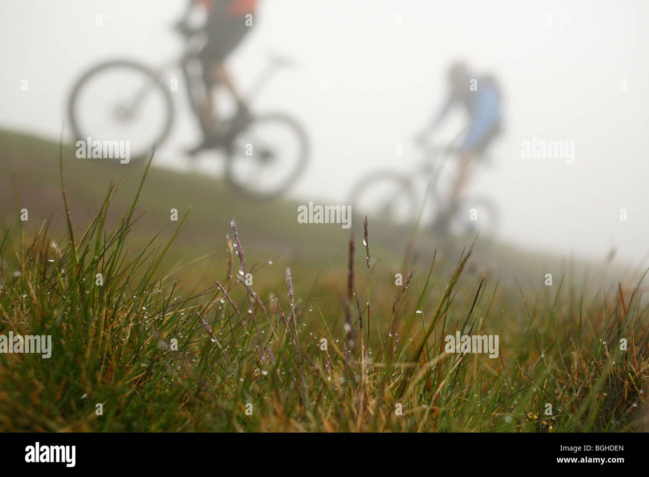 Two mountain bikers ride a misty trail at Howgill Fells, United Kingdom Stock Photo