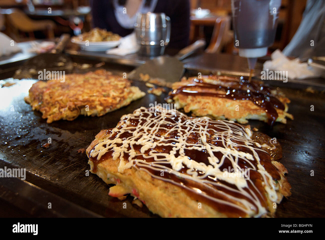 Okonomi yaki. Japanese style savoury pancakes being cooked on a hot plate. Japan Stock Photo