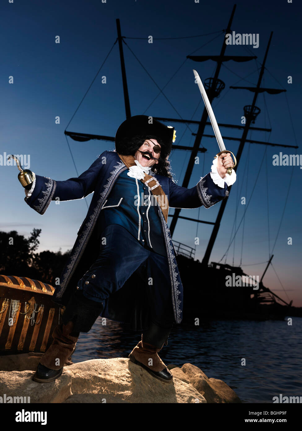 License available at MaximImages.com - Pirate ashore with a treasure chest and a wrecked old ship in the background Stock Photo