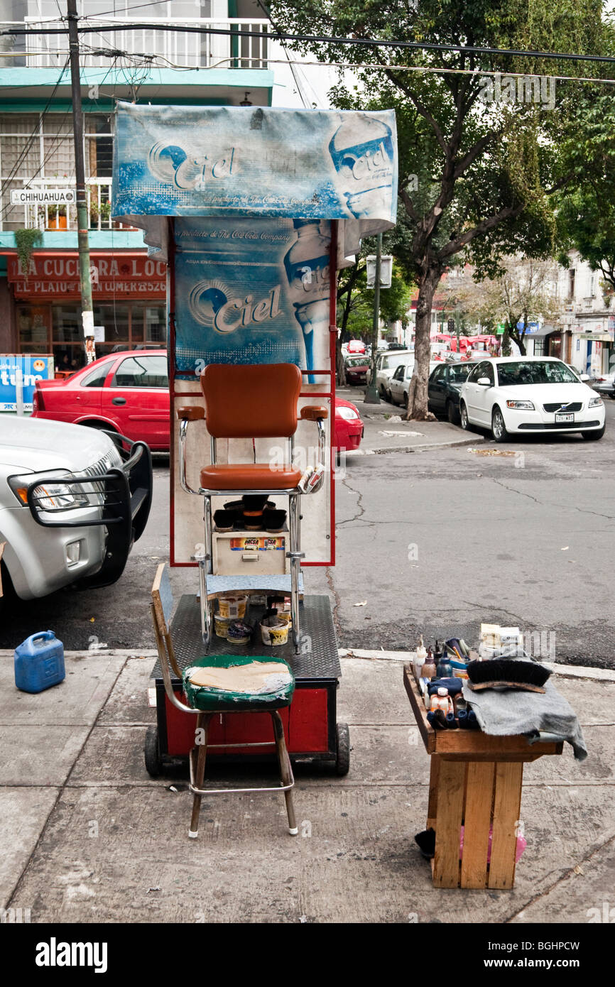 charming street corner shoeshine stand with funky old chairs & makeshift canopy draped with bottled water advertising Mexico Stock Photo