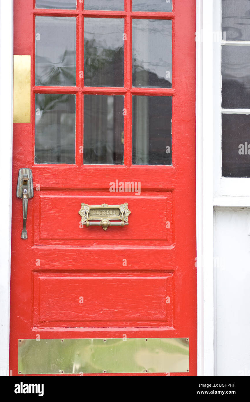 A Vibrantly Painted Red Door With Brass Accents Consisting Of