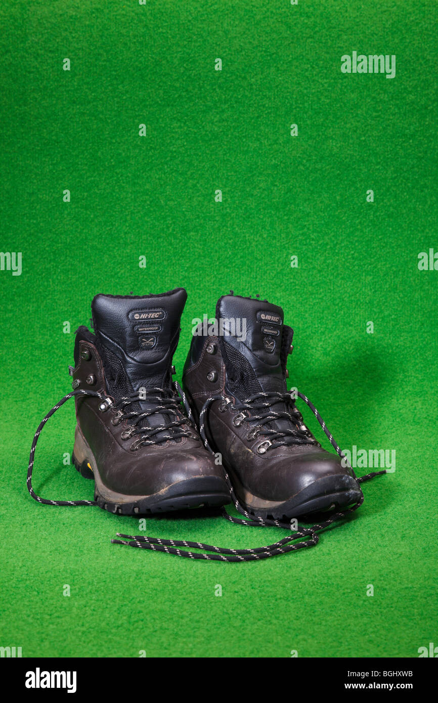 A pair of used Hi Tec walking boots on a green backdrop. Stock Photo