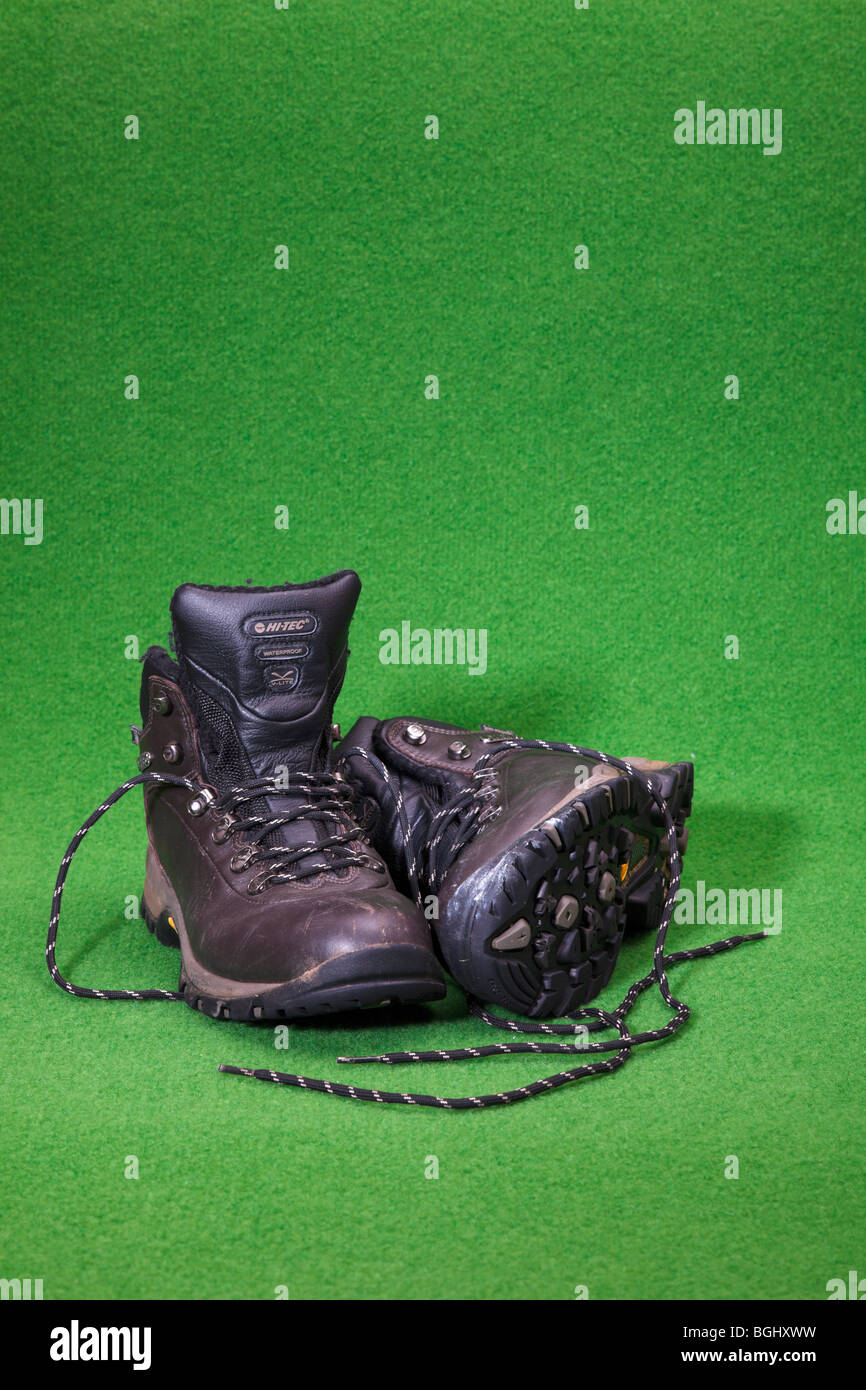 A pair of used Hi Tec walking boots on a green backdrop. Stock Photo