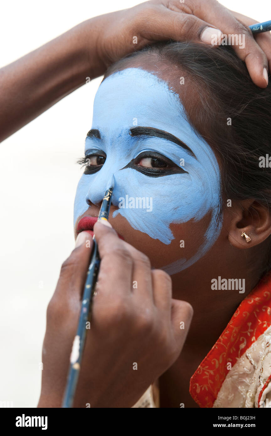 Indian girl having her face painted blue to be made up as an india deity. Andhra Pradesh, India Stock Photo