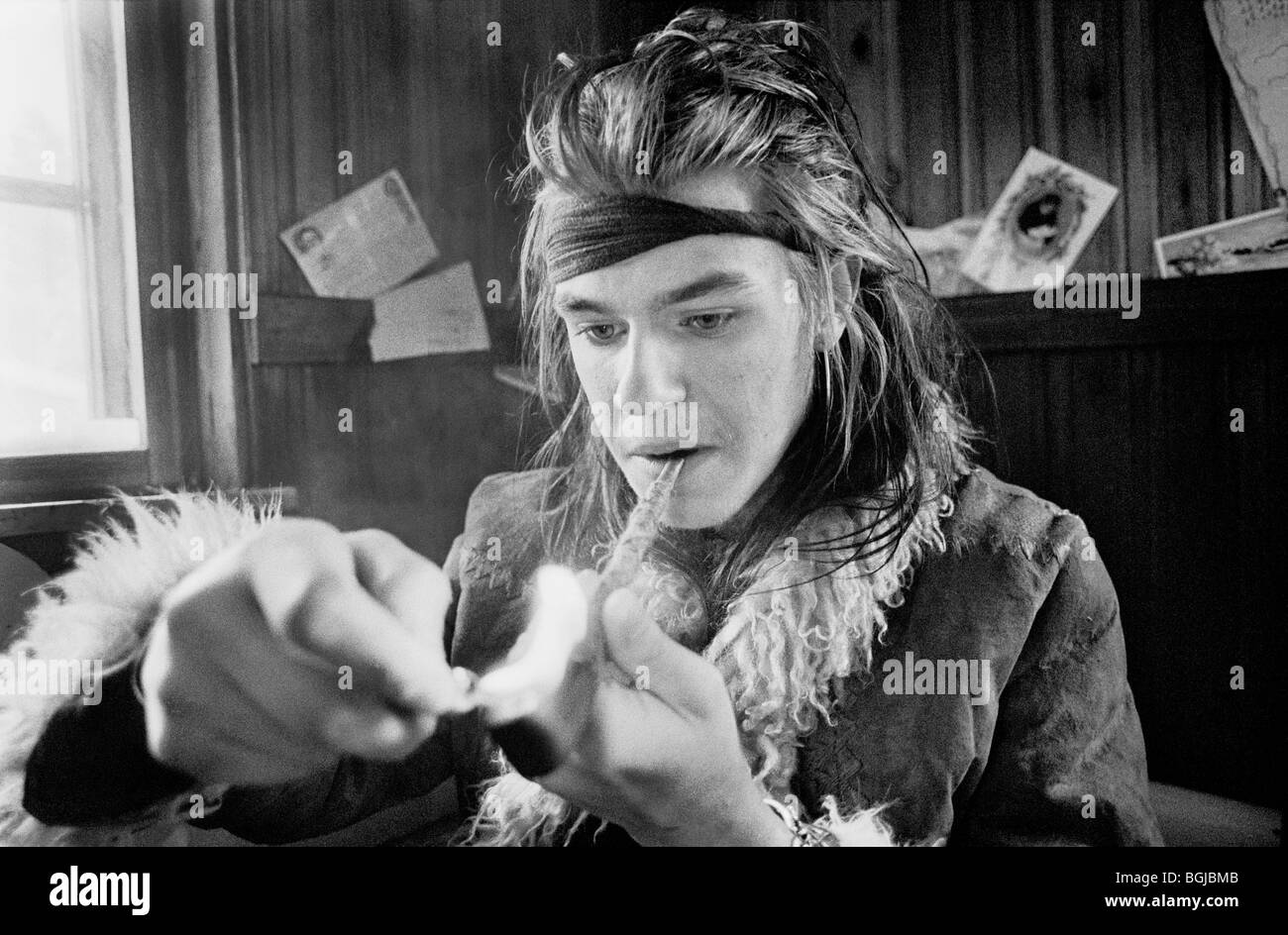 Young man lighting a pipe at alternative lifestyle commune in Skogsnäs ...