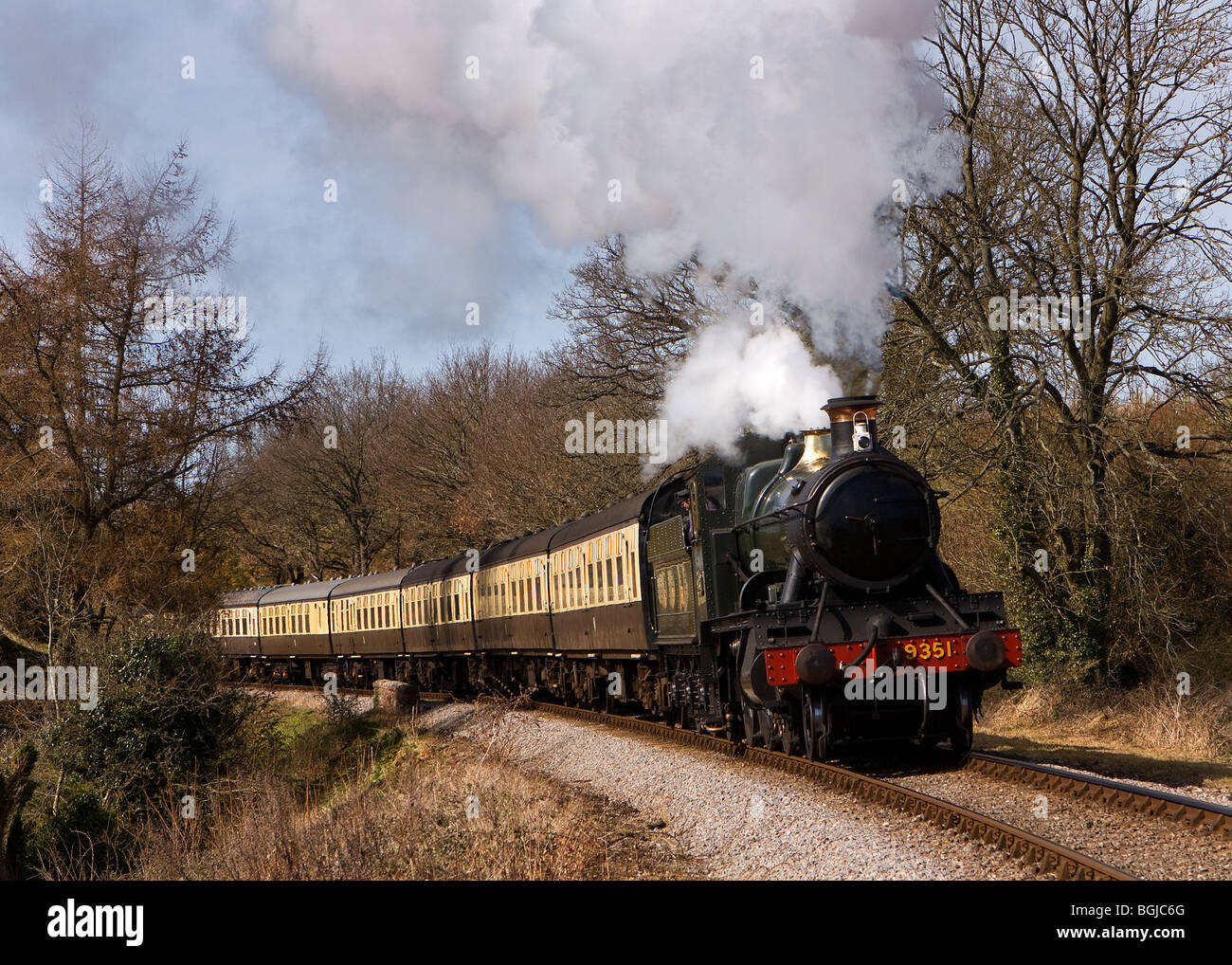 In spring sunshine, Ex GWR 9351 passes Water Farm bridge on the West Somerset Railway, UK with a train for Bishops Lydeard Stock Photo
