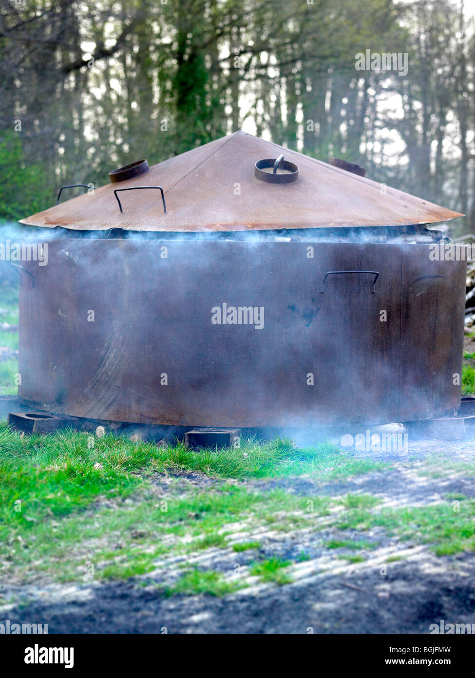 A kiln smokes as it makes charcoal Stock Photo Alamy