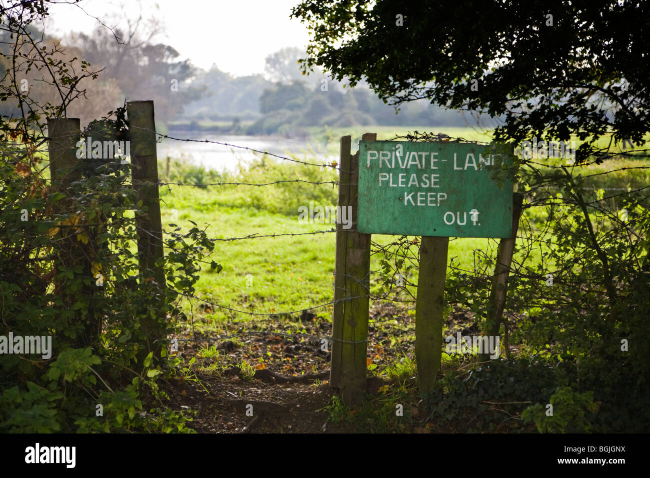 Fence and notice marking a boundary. Sign reads 'Private Land Please Keep Out'. Borders of Hampshire and Dorset, UK. Stock Photo