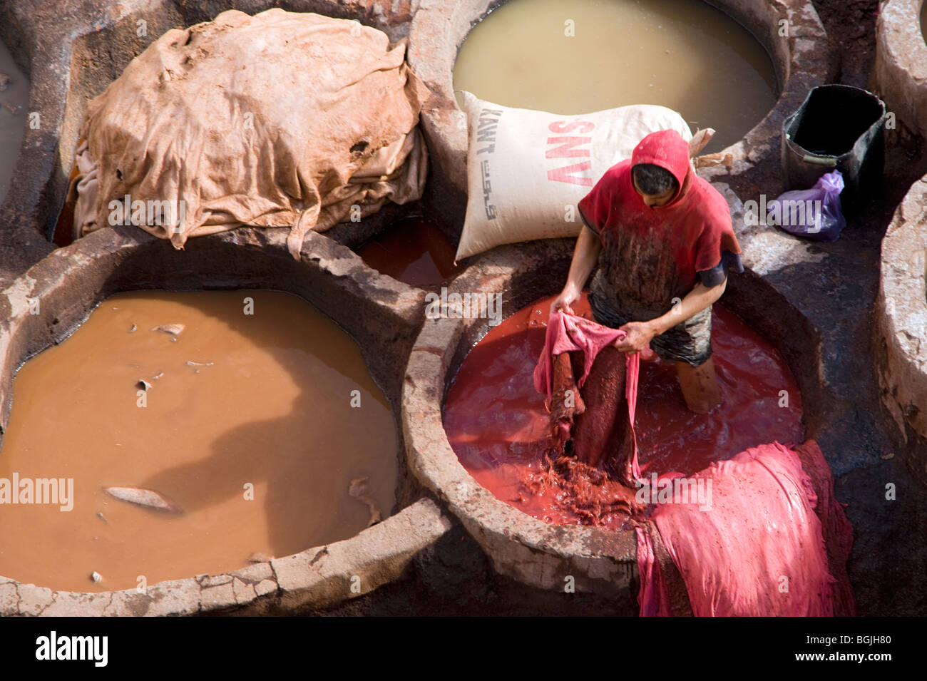 A man in vat of red dye at the tanneries in Fes Morocco Stock Photo
