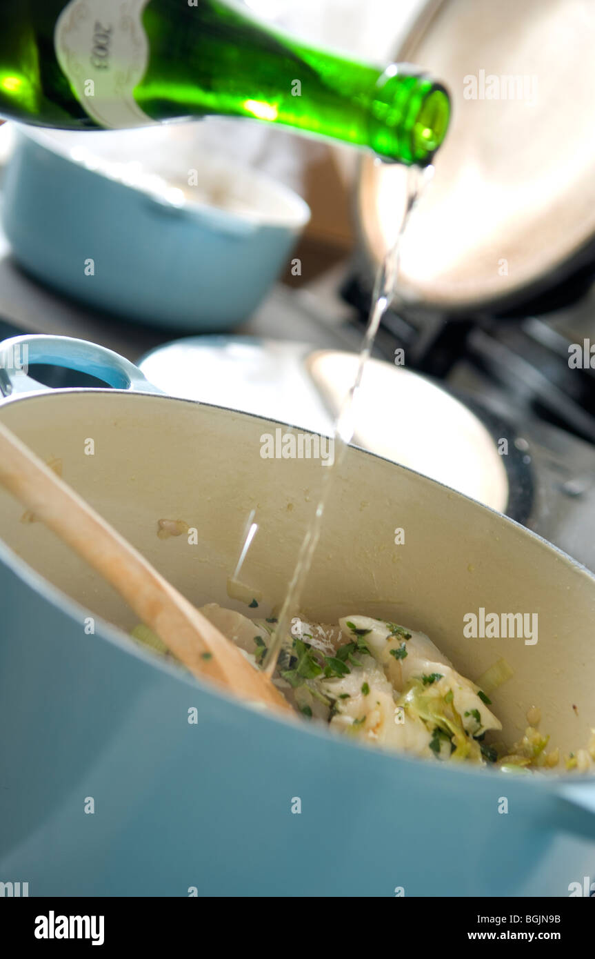 Adding wine to casserole dish on stove. Stock Photo