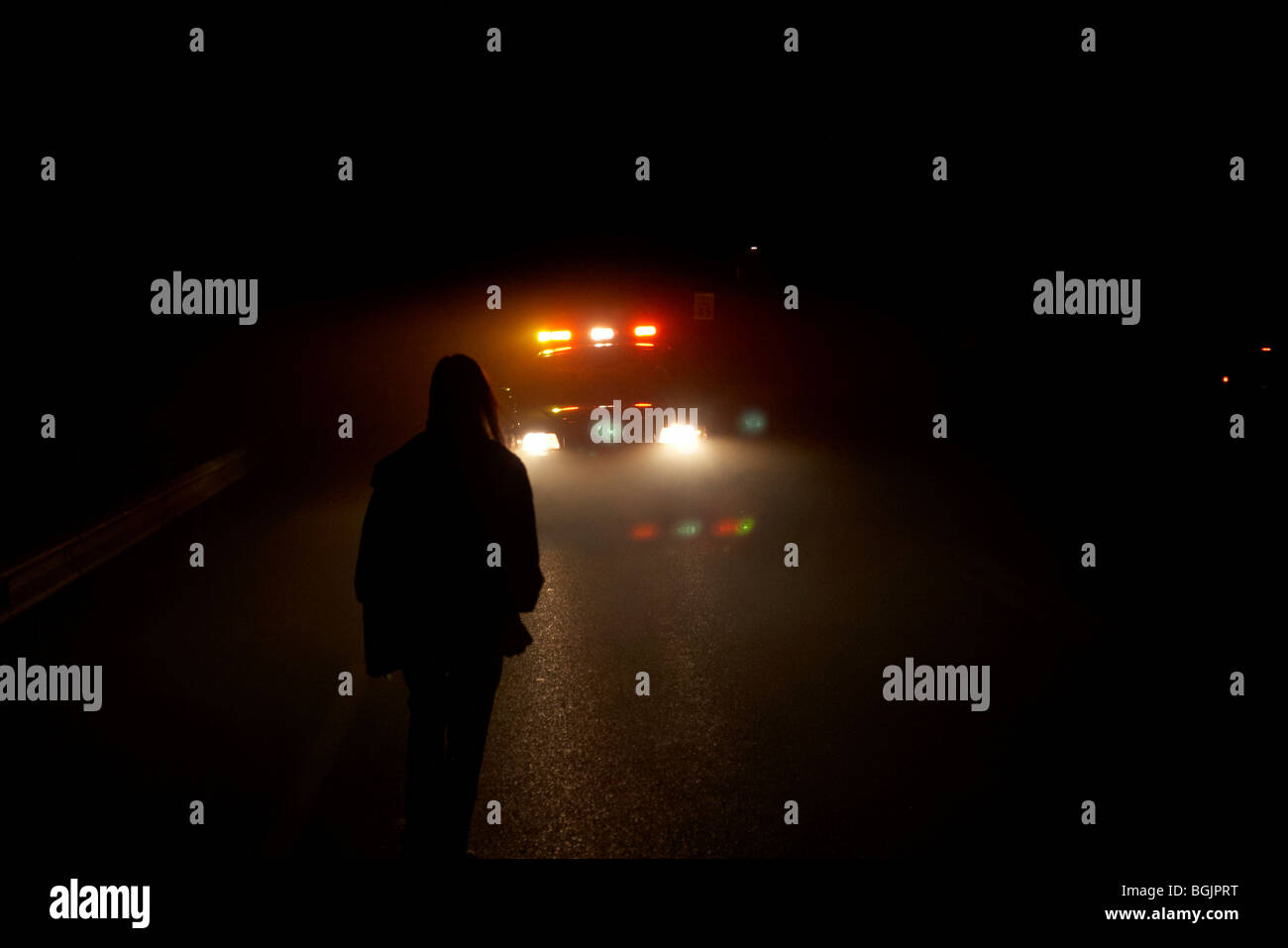 A woman standing in front of a police patrol car on a foggy night Stock Photo